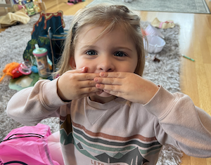 A child covering her mouth, silently