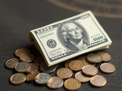 A $100 bill and some change on a table, reflecting a small amount of money 