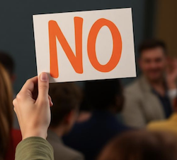 A person holding up a "no" sign, indicating no to further performance on an agreement